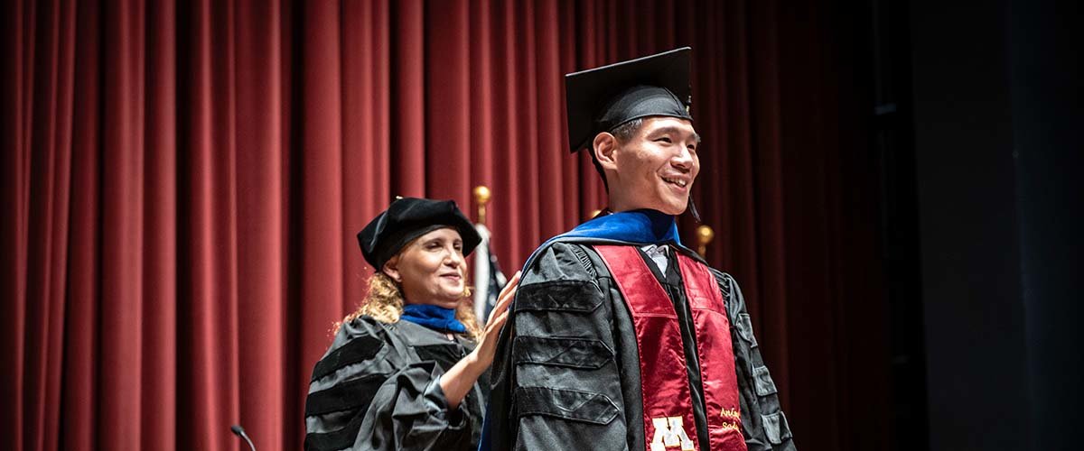 CFANS graduate student gets hooded by their advisor during commencement.