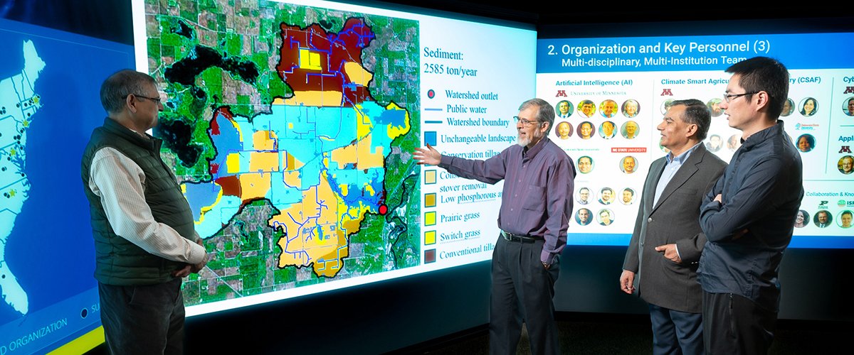 Four men stand before a large sediment map