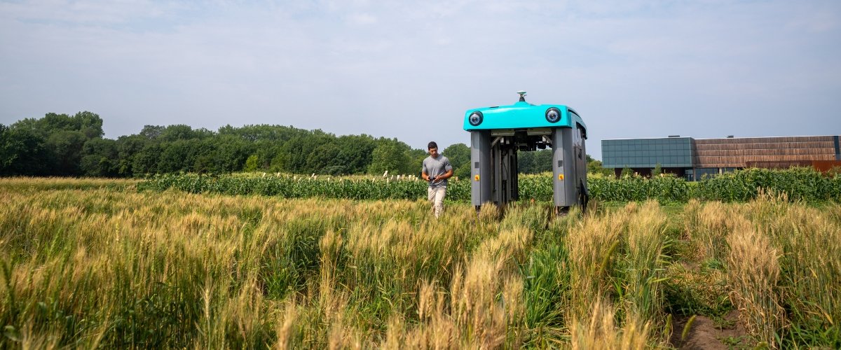 A person and a rover in a field on the St. Paul campus of the University of Minnesota