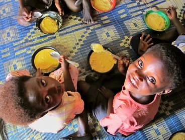 Two small children sit on the floor and look up at the camera.