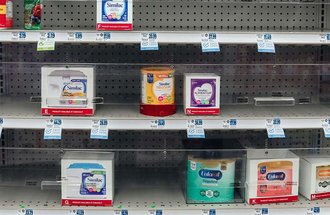 Infant formula on a nearly empty retail shelf.