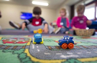 Three kids sitting next to each other playing at a daycare center.