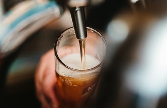 Beer from a tap being poured into a pint glass.