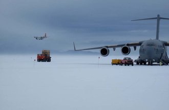 A New York Air National Guard LC-130 landing while a U.S. Air Force C-17 unloads.