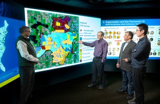 Four men stand before a large sediment map