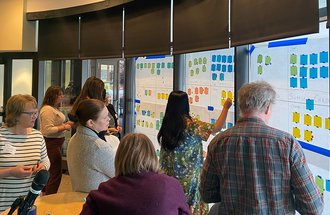 Several individuals standing by a wall with sticky notes on it